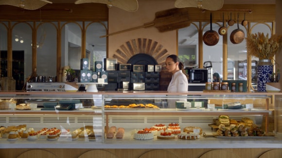A woman standing behind a pastry counter